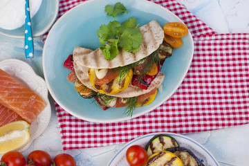 Tortilla, traditional Mexican food. Lunch with vegetables and salmon on the grill, healthy food. Place for text. Dietary food
