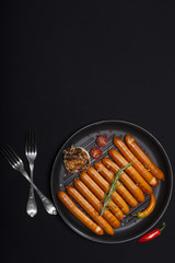Wiener Sausages in a pan on black background with copy space