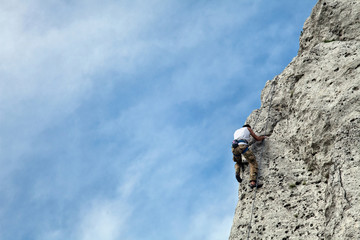 Man climbs to the top of the mountain. Rock climbing with belaying. Learning to climb a mountain. To reach a top.