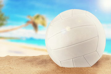 White volleyball ball at the beach on a sunny day. Tropical landscape in background.