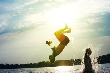Glückliche junge Menschen laufen und springen am See beim Sonnenuntergang © Thaut Images