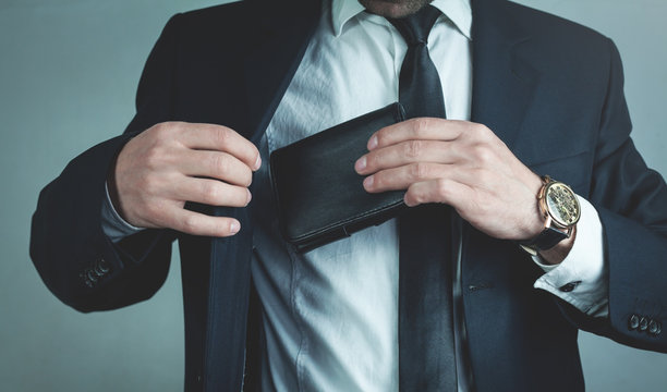 Businessman pulls his leather wallet into suit pocket.