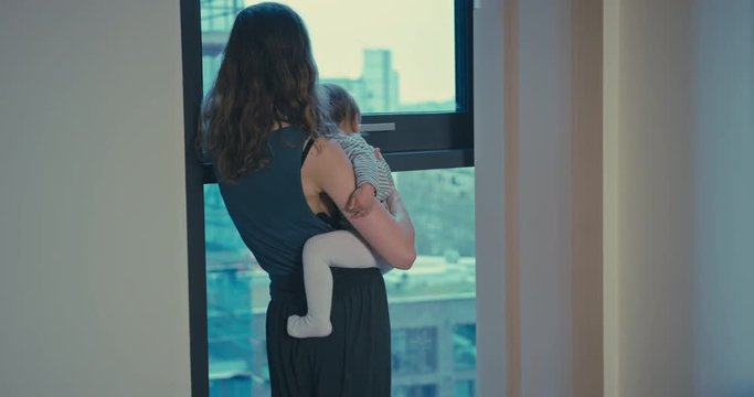 Mother and toddler enjoying the view in city apartment
