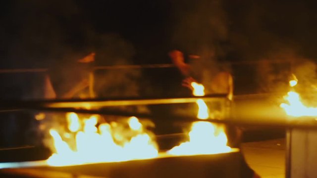 Two ninja men in black clothes and masks fighting in night on background fire flame