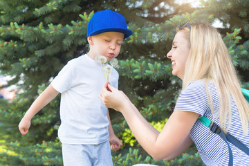 Fototapeta premium Mother and little son blowing on a dandelion.
