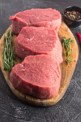 Raw beef meat with rosemary, thyme and chili pepper on a cutting board. Close-up. Vertical view