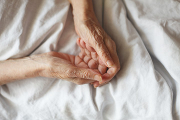 Old hands on a white background. Grandmother in bed.