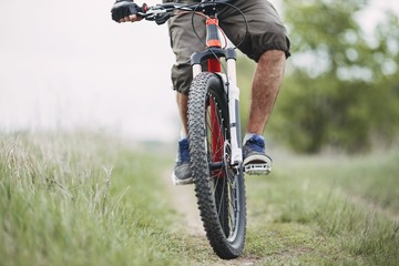 Cross-country riding, cycling, activity and sports. Man riding a bicycle at countryside, low angle view