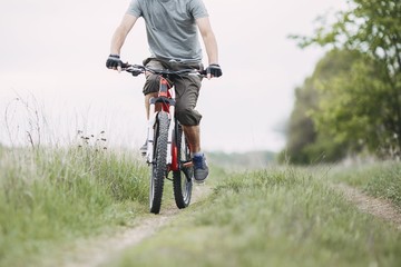 Fototapeta na wymiar Low angle view of man riding a bicycle along country road. Environmentally friendly transport, outdoor activity, healthy lifestyle