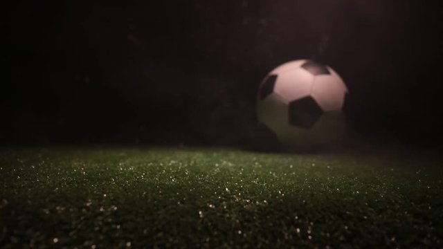 Slider shot. Traditional soccer ball on soccer field. Close up view of soccer ball (football) on green grass with dark toned foggy background. Selective focus