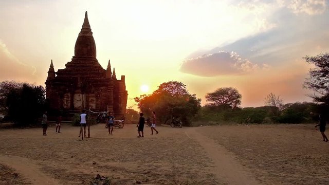 BAGAN, MYANMAR - FEBRUARY 26, 2018: Group of teens play chinlone (caneball) - traditional Burmese sport, amid the ancient temples of Old Bagan archaeological site on sunset, on February 26 in Bagan