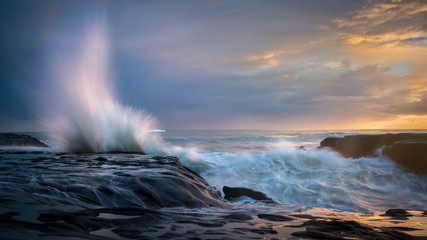 Splashing waves at Sunset, Muriwai beach, west Auckland, New Zealand