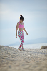woman wearing sport suit walking on white sand beach