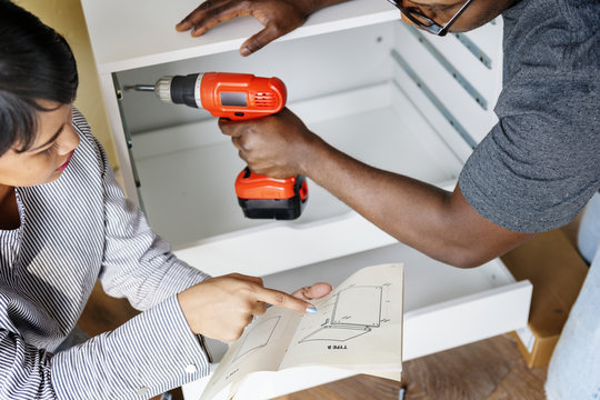 Man using electronic drill install cabinet - Powered by Adobe