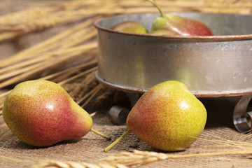 Yellow and red pears on burlap and in vintage pan decorated with wheat grass