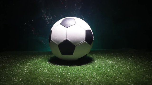 Slider shot. Traditional soccer ball on soccer field. Close up view of soccer ball (football) on green grass with dark toned foggy background. Selective focus