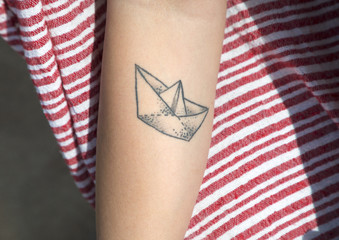Barchetta di carta tatuata sul braccio