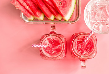 summer drinks concept. watermelon slices, ice cubes and smoothies in mason jar on pink fashion...