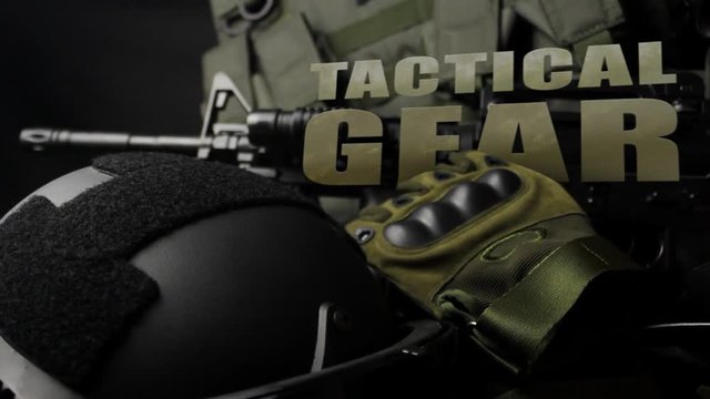 Photo of a tactical military vest, rifle, gun, helmet with glasses close-up view and cartrige belt laying on black cloth table background with text.