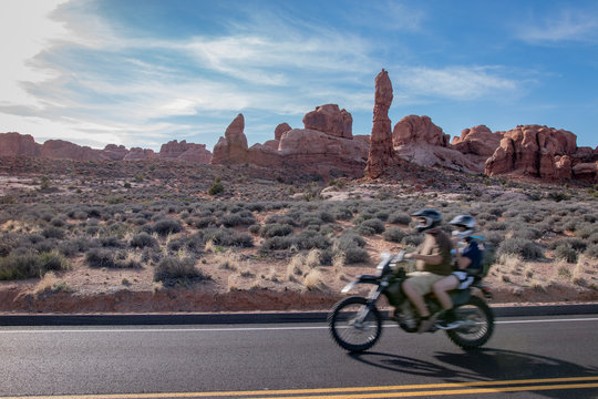 Father and son driving past desert on motorbike