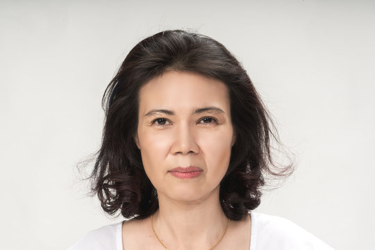 Portrait of beautiful mature asian woman with curly hair style smiling with joyful and charming on white background isolate. Close up happy and cheerful older lady wear white shirt health care concept