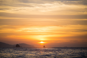 Obraz premium 水平線に沈む太陽と島と船