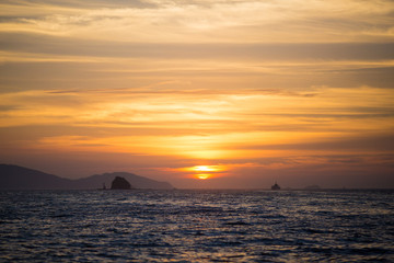 水平線に沈む太陽と島と船