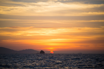 水平線に沈む太陽と島と船