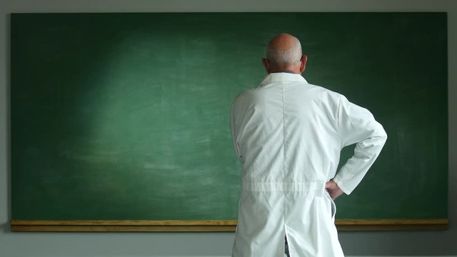 Man in labcoat looking at blank chalkboard