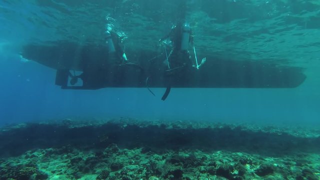 Three scuba divers swim to the ladder diving boat, Indian Ocean, Fuvahmulah island, Maldives

