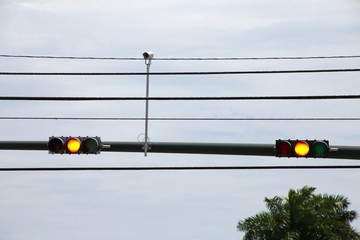 Yellow Traffic Lights with Camera on Pole Against Cloudy Overcast Sky