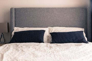 Bed with wrinkle white duvet in narrow condominium.