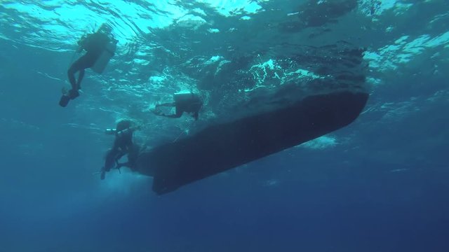 Group scuba divers swim to the ladder diving boat, Indian Ocean, Fuvahmulah island, Maldives
