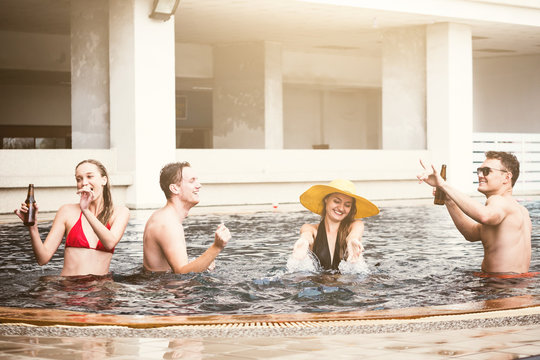 Group of friends enjoying vacation in summer time. Young people having fun dancing in swimming pool - Powered by Adobe