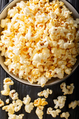 Tasty popcorn with cheese cheddar and parmesan in a bowl macro. Vertical top view