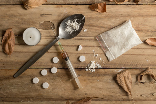 Drug addiction objects rustic wooden background texture with dried autumn leaves - conceptual top view photo