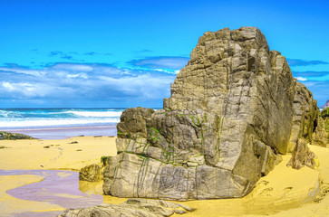 Tropical beach with stones. Sand beach view with cloudy sky.