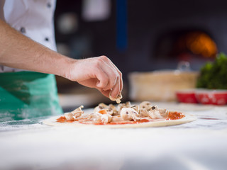 Obraz na płótnie Canvas chef putting fresh mushrooms on pizza dough
