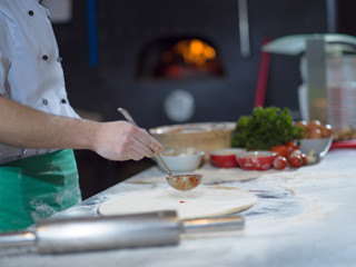 Obraz na płótnie Canvas chef putting cut sausage or ham on pizza dough