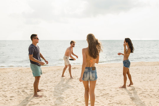 Group of friends playing at the beach on summer holidays
