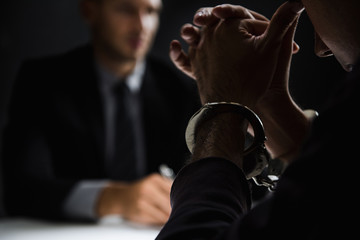 Criminal man with handcuffs in interrogation room - obrazy, fototapety, plakaty