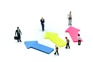 Miniature people: young Businessman standing in front of arrow pathway choice using as Business decision concept.