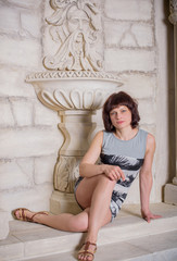Fototapeta premium Portrait of mature woman near antique rome sculpture in the historical interior. Greece style 