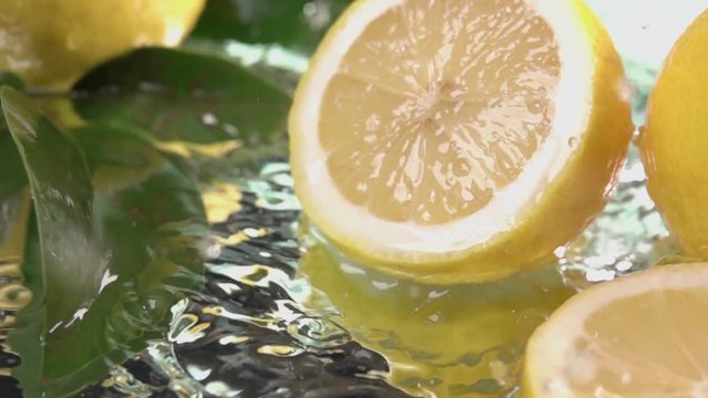 Close up Lemon half slice hits on fresh water surface . Slow motion shot