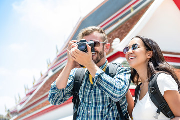 Interracial tourist couple taking photos during summer holiday trip in Bangkok Thailand
