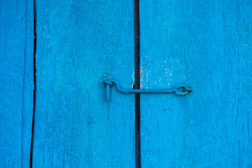 The old blue door is closed on the hook. Background and texture of an old wooden door
