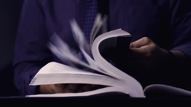 Holding the book with two hands, Open book in the black background, cinemagraph style, footage, video 60 fps