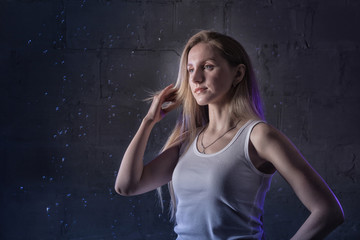 Naklejka premium Portrain of the girl in the white shirt with water drop in a dark room illuminated by light during a photoshoot with water