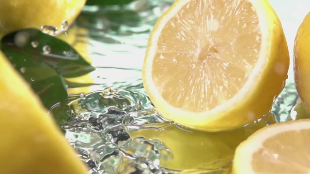 Lemon hits orange juice surface and splits into halves. Slow motion shot. Close up