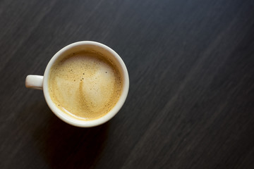 Cup of coffee on a wooden background. Kind from above.